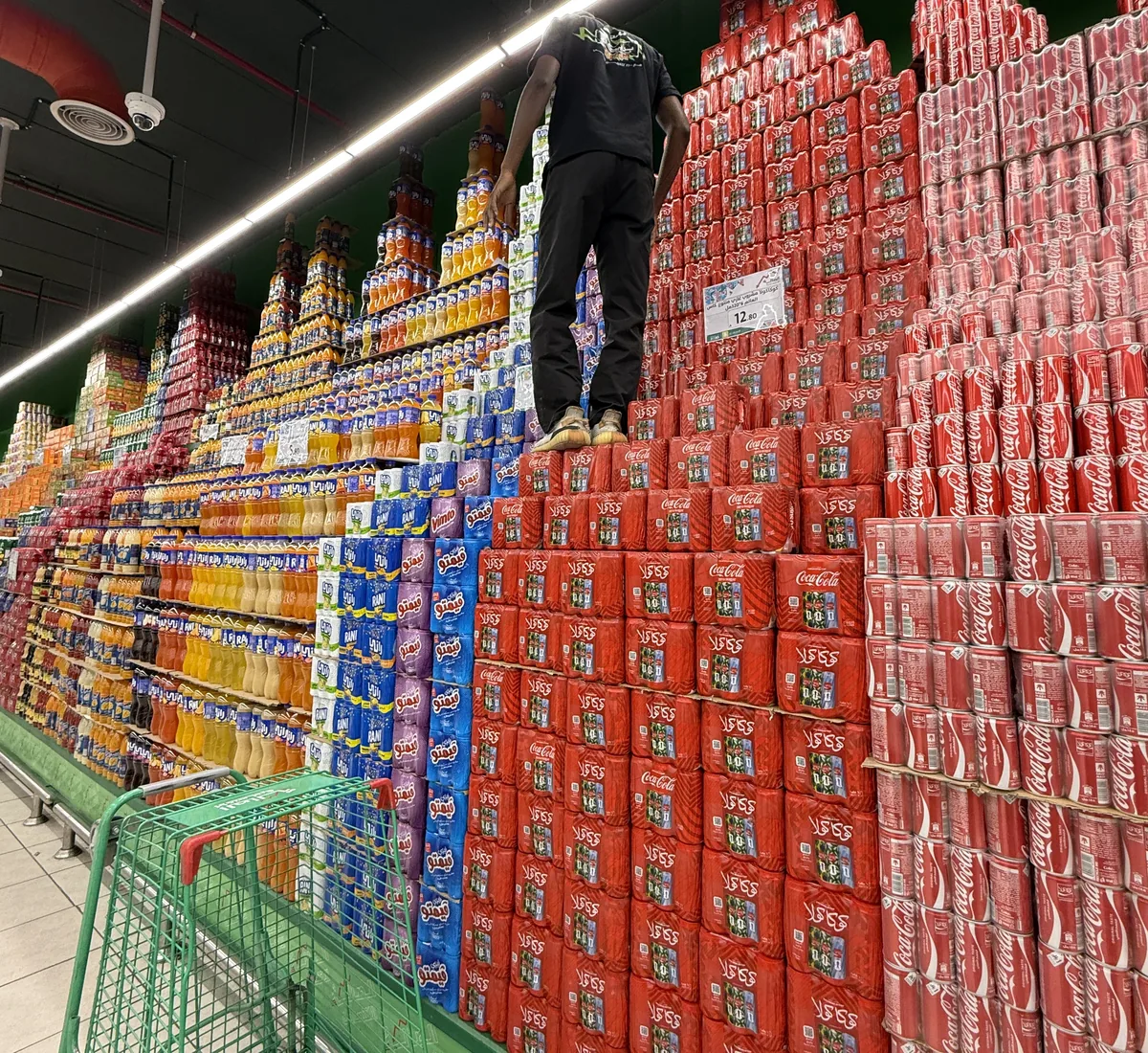 Store team building a large promotional mass display of stacked beverages